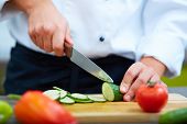 image of food  - Image of male hand with knife cutting cucumbers on wooden board - JPG 