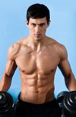 foto of dumbbells  - Handsome muscular man with sexy body uses his dumbbell to exercise flexing bicep muscle - JPG 