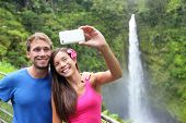stock photo of multicultural  - Couple tourists taking self portrait with camera phone on Hawaii - JPG 