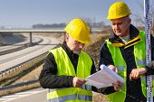 foto of reflection  - Land surveyors on highway reading geodesist plans use tacheometer - JPG 