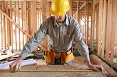 stock photo of buildings  - A man working building a home and measuring some wood - JPG 