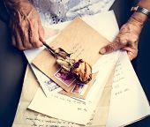 Elderly woman holding old letters with dry rose in her hands