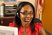 pic of receptionist  - A beautiful African American receptionist wearing a headset and glasses smiling as she looks toward the camera - JPG 