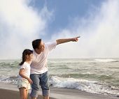 stock photo of sunset  - father pointing and little girl looking it on the beach - JPG 
