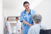 stock photo of mid adult  - Nurse standing next to a patient while holding her hands in hospital ward - JPG 