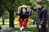 image of cerebral  - Father pushing disabled boy in special needs handicap swing - JPG 