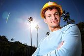 image of young adult  - Construction worker in yellow hard hat over blue sunny sky - JPG 
