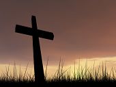 picture of religion  - Concept conceptual black cross or religion symbol silhouette in grass over a sunset or sunrise sky with sunlight clouds background - JPG 