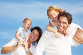 pic of family  - young happy family having fun outdoors dressed in white and with blue sky in background - JPG 