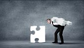 picture of puzzle  - Team of business people collaborate holding up jigsaw puzzle pieces as a solution to a problem - JPG 