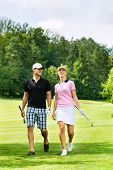 foto of golf  - Young sportive couple playing golf on a golf course - JPG 