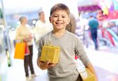 picture of youngster  - Portrait of happy child holding gift box with his family on background - JPG 