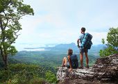 pic of valley  - Young tourists with backpacks enjoying valley view from top of a mountain - JPG 