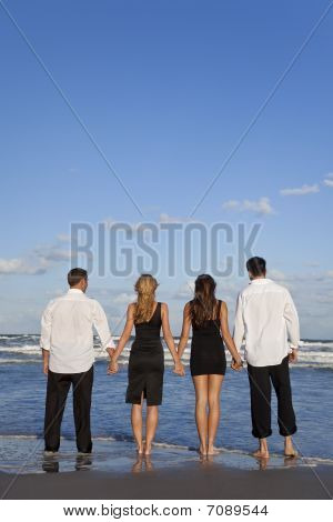 Two old people walking on the beach holding hands.