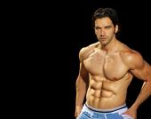 stock photo of fitness  - Sexy male fitness model on black background with lots of copy space - JPG 