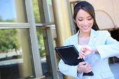 stock photo of watch  - A pretty asian business woman looking at watch at office building - JPG 