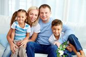 image of portrait  - Portrait of happy family with two children sitting at home - JPG 