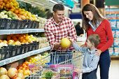 stock photo of food  - woman with man and child choosing melon fruit during shopping at vegetable supermarket - JPG 
