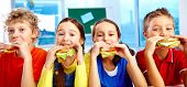 picture of youngster  - Four schoolkids looking at camera while having lunch during break - JPG 