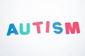 foto of spell  - Autism spelled out in pink green and blue on white background - JPG 