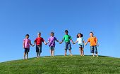 stock photo of group  - Group of kids standing on grass hill with blue sky - JPG 