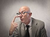 stock photo of fraud  - Lying businessman observing his long nose - JPG 
