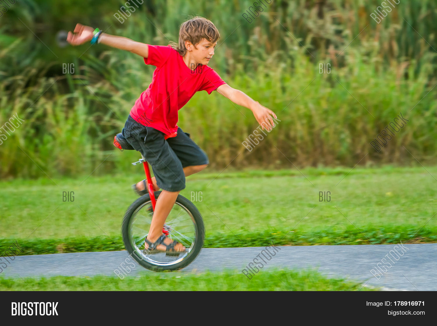 outdoor portrait of young boy riding a unicycle (one wheel bike) on