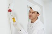 pic of industrial  - One male house painter worker painting and priming wall with painting roller - JPG 