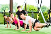 stock photo of fitness  - Group of people exercising with suspension trainer in fitness club or gym - JPG 