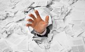 picture of finance  - Hand reaches out from big heap of crumpled papers - JPG 
