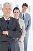 foto of leadership  - Smiling mature manager standing upright in front of his young business team - JPG 