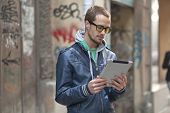 pic of computer  - Young man with yellow glasses use iPad tablet computer on street - JPG 