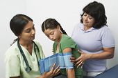 picture of pressure  - Female doctor checking blood pressure of girl standing with mother - JPG 