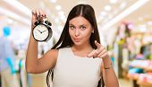foto of holding  - Young Woman Holding Clock And Pointing at a mall - JPG 
