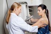 picture of medical doctors  - Mature female doctor assisting young patient undergoing mammogram - JPG 