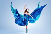 stock photo of grace  - Beautiful ballet dancer with flowing blue fabric dancing with grace in studio - JPG 