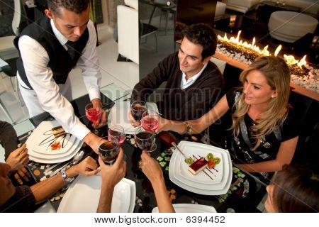 Picture or Photo of Group of people at a restaurat having dinner being served by a waiter