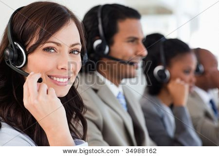 Picture or Photo of Smiling worker doing her job with a headset while looking at the camera