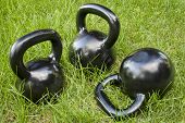 stock photo of fitness  - three heavy iron  kettlebells in green grass  - JPG 