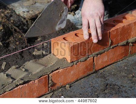 Picture or Photo of Construction worker laying bricks showing trowel and guideline.