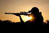 pic of sunset  - Silhouette of a young man shooting with a long rifle against sunset sky - JPG 