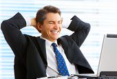 foto of businessmen  - Happy smiling businessman working with laptop in the office - JPG 