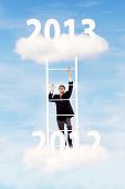 picture of gain  - Businessman climbing upward on the stair of cloud from the year of 2012 to 2013 to gain his success - JPG 