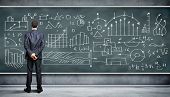 stock photo of people  - Business person standing against the blackboard with a lot of data written on it - JPG 