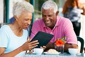 stock photo of outdoor  - Senior Couple Using Tablet Computer At Outdoor Cafe - JPG 