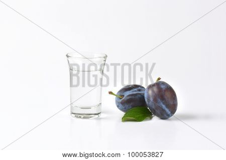slivovitz (plum brandy) and fresh plum on white background
