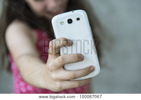 Teenage girl taking a selfie with her phone. Focus on smart phone