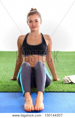 Beautiful young woman relaxing after exerscises on the grass 