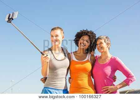 Smiling sporty women taking selfies with selfiestick at promenade