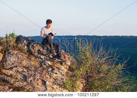 Man Sits On The Cliff And Reading A Book